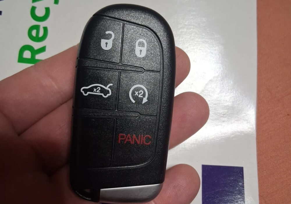 Five button push to start smart car key fob held in hand