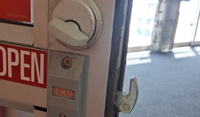 Mobile locksmith checking a storefront door deadbolt in Waco, TX