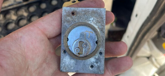 Mobile locksmith holding a lock at the service van in Texas